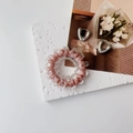 Detail of pink spiral telephone cord hair tie and silver metal hoop earrings on a display - Pink