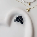 Detail shot of a glossy black bow hair clip on a heart-shaped tray with jewelry - Painted Black (Metal)