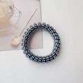 Detail of spiral hair tie with black and white stripes next to a lemon tea cup - Black Stripe