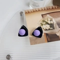 Detalle macro de pinza de pelo oreja de gato con perla lila sobre bandeja de vidrio - Morado