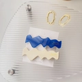 Dettaglio di fermagli per capelli in acetato ondulato blu navy e crema su scheda - Stile a Onda Grossa