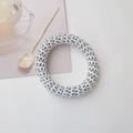 Detailed view of a white spiral telephone cord hair tie featuring black polka dots on desk - White Polka Dot