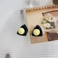Detalle de dos pinzas negras con forma de oreja de gato para niños sobre bandeja - Amarillo