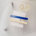Dettaglio di fermagli per capelli in acetato blu e beige con logo Amy bear su cartoncino - Stile Dritto