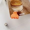 Close-up of matte orange small hair claw clip on wave pattern acrylic tray - Matte Orange