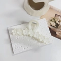 Detail of white matte floral hair claw clip with daisy design on textured background - Matte White