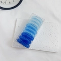 Detail of gradient blue spiral hair ties in a transparent box on a white surface - Gradient Blue