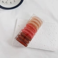 Macro detail of gradient spiral hair ties in a clear storage box over a white texture - Gradient Red
