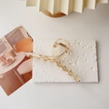 Detail of transparent amber-dotted hair claw clip on white textured stone background - L / Transparent Champagne
