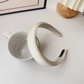 Detail of a beige padded sponge headband on a white cup with a Hand Made label - Cream