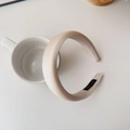 Close-up of handmade label on beige satin padded sponge headband placed on a ceramic cup - Khaki