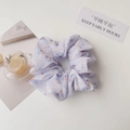 Close-up of light purple floral scrunchie with soft pastel pattern on a clean white desk - Gold Wire Flower