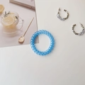 Still life of blue spiral hair tie and silver geometric earrings on a clean white desk - Transparent Blue
