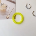 Macro shot of a yellow spiral telephone cord hair tie with a translucent resin texture - Clear Yellow Green