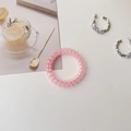 Detailed view of a semi-transparent pink spiral hair coil on a clean minimalist background - Transparent Pink