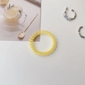 Close-up of yellow spiral hair tie and silver hoop earrings on a clean white background - Transparent Yellow
