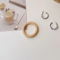 Detail of a beige spiral hair tie alongside silver cubic zirconia hoop earrings on white - Forest Khaki