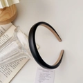 Detail view of a padded black leather headband resting on a glass for a classic look - Leather / Black