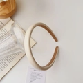 Detail of cream matte leather padded headband with non-slip lining against a book - Leather / Cream