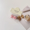 Detailed macro view of two pink camellia flower hair clips in their elegant packaging - Rose Hair Claw