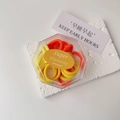 Detail view of yellow and orange elastic hair ties in a clear hexagonal storage box - Boxed Orange Yellow