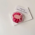 Close-up of high elasticity hair ties in a clear gift box on a white textured stone base - Pink Box