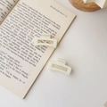 Gros plan de pinces à cheveux carrées crème mat pour un style minimaliste - Carré Blanc