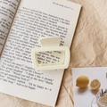 Close-up of matte cream square hair claw clip on a book page with natural lighting - Glossy White
