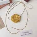 Macro shot of yellow handmade fabric rose choker necklace on a minimalist warm background - Yellow