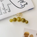 Détail de la pince à cheveux vert olive avec cinq sphères dégradées sur un bureau - vert olive