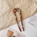 Close-up of acetate U-shaped hair fork with green marble texture and gold lettering - Blue and Red Texture