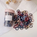 Close-up of candy colored hair ties in a transparent storage jar with pink lid - Dark Colors Ice Cream Cup