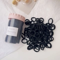 Close-up of black high-elastic hair ties in a clear storage jar with pink lid - Black Ice Cream Cup