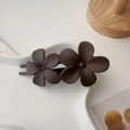 Dettaglio del doppio fermaglio per capelli a fiore marrone opaco su vassoio bianco - Caffè Floreale