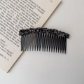 Close-up of a black hair comb with glittering rhinestones on a decorative book background - Rhinestone Style / Rhinestone Hair Comb - Black
