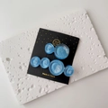 Close-up of blue resin wavy round hair clips with pearl luster on a display card - One Pair / Blue