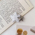Detailansicht der Y2K Stern-Haarklammer mit Pailletten auf einem Buchhintergrund - Weiß und Silber