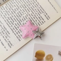 Detailansicht der pinkfarbenen Y2K Stern-Haarklammer mit Glitzer auf Buchhintergrund - Rosa und Silber
