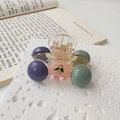 Detail einer mattierten Perlen-Haarklammer mit Kirschdesign auf weißer Steinfläche - Blau Violett