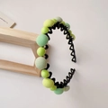 Dettaglio del cerchietto ondulato per bambina con perle colorate in tessuto e resina - Verde Matcha Cerchietto Tondo