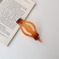 Close-up detail of a matte amber braided twist hair clip on an open book background - Matte Amber