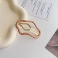 Dettaglio ravvicinato di una clip per capelli rosa ondulata su vassoio minimalista - Caffè latte