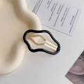 Dettaglio di un fermaglio per capelli nero ondulato con clip in metallo dorato su vassoio - Nero