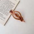 Detail view of a matte brown twist hair claw clip on an aesthetic book background - Matte Milk Tea
