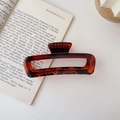Close-up detail of a large amber tortoiseshell acrylic hair claw clip on a book - Amber