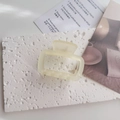 Primer plano de una pinza para el pelo mate blanco crema sobre piedra texturizada - Amarillo Claro
