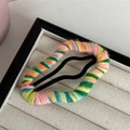 Dettaglio ravvicinato di un fermaglio per capelli in maglia arcobaleno su scatola - Misto Arancione Giallo Verde