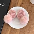Dettaglio di un fermaglio per capelli a fiocco rosa in maglia con pompon morbidi - Rosa