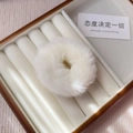 Macro shot of fluffy white faux fur hair tie showing soft texture in jewelry display box - White
