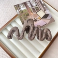 Detail of khaki wavy hair claw clip with black abstract lines on a jewelry box - Brown